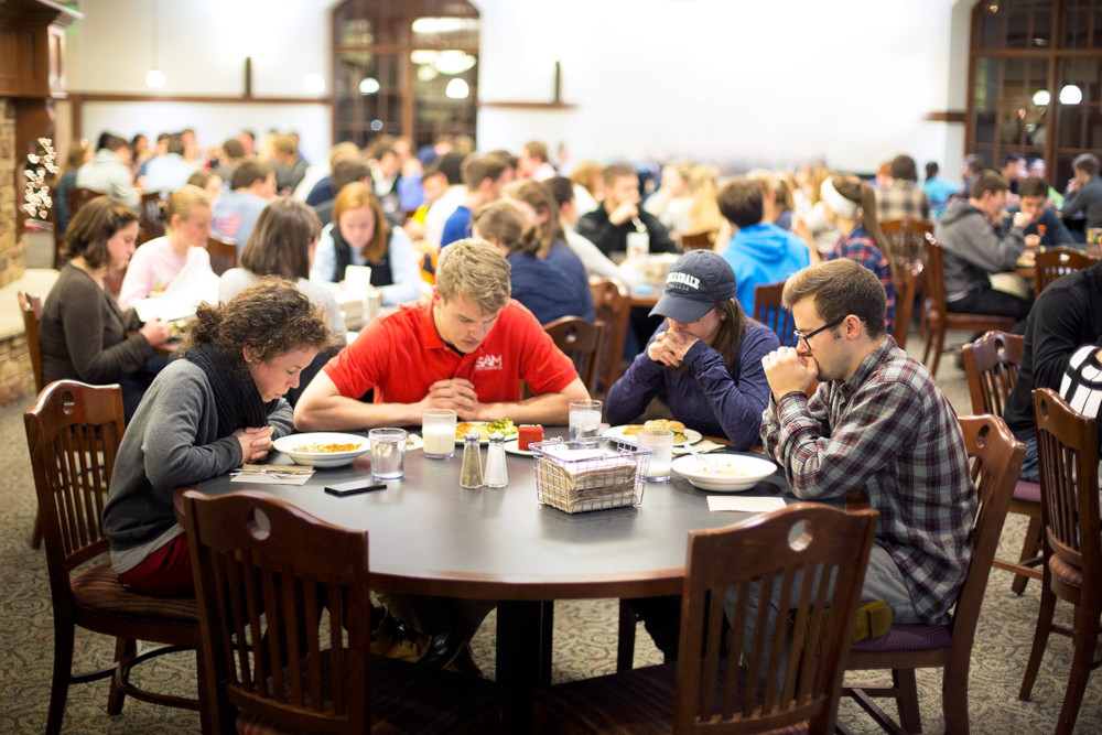 Students praying over their meal in the Knorr Family Dining Room.